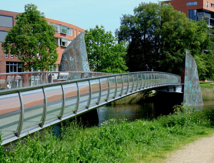 Een brug die over het groen heen gaat met bomen op de achtergrond