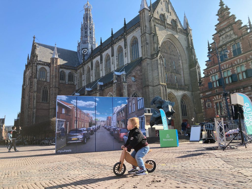 kind op loopfiets rijdt over de markt in Haarlem