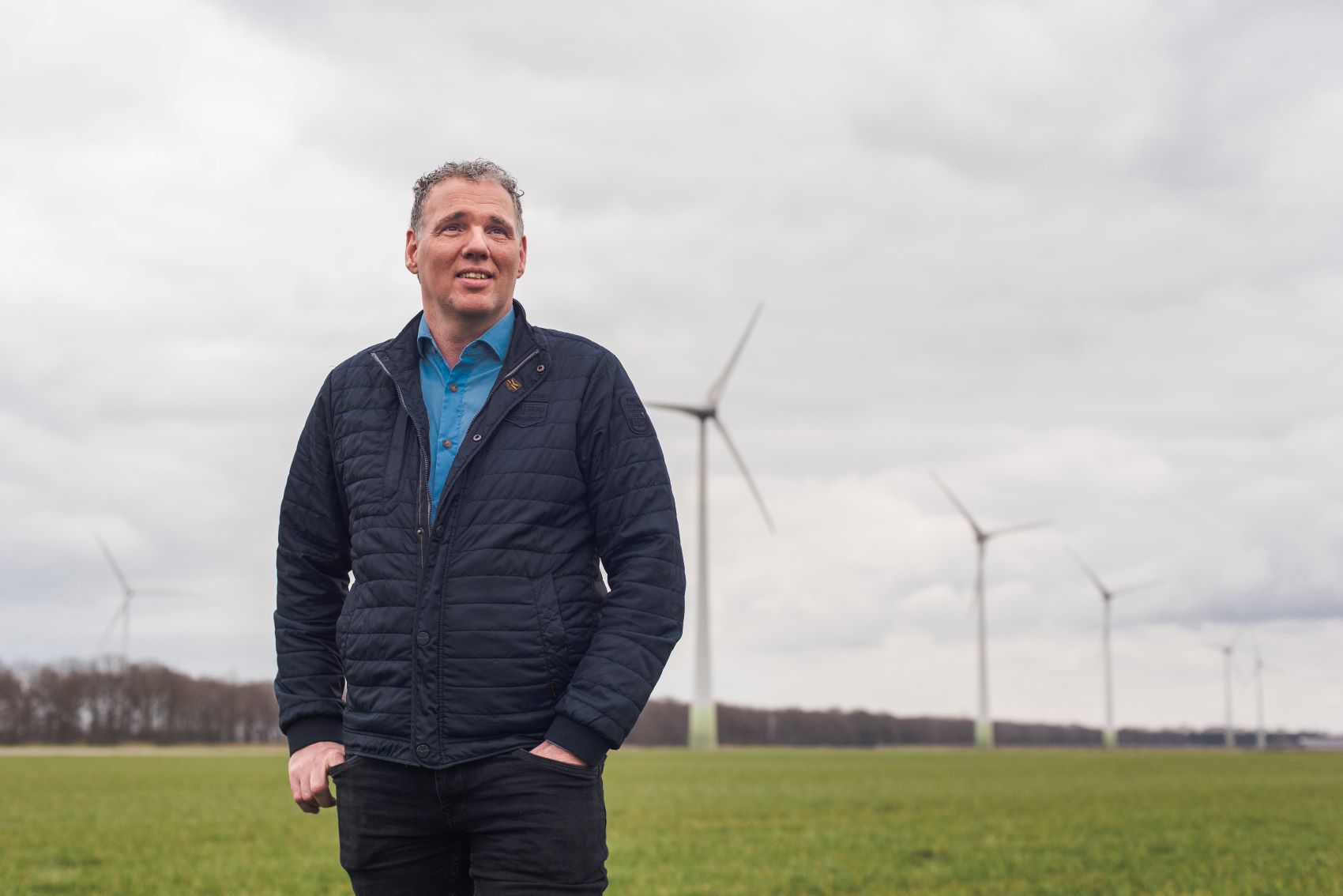 Agrariër staat op zijn akker naast zeven windmolens