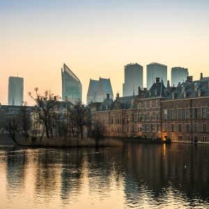 Het buitenhof in Den Haag met de vijver ervoor en hoogbouw op de achtergrond, warm licht