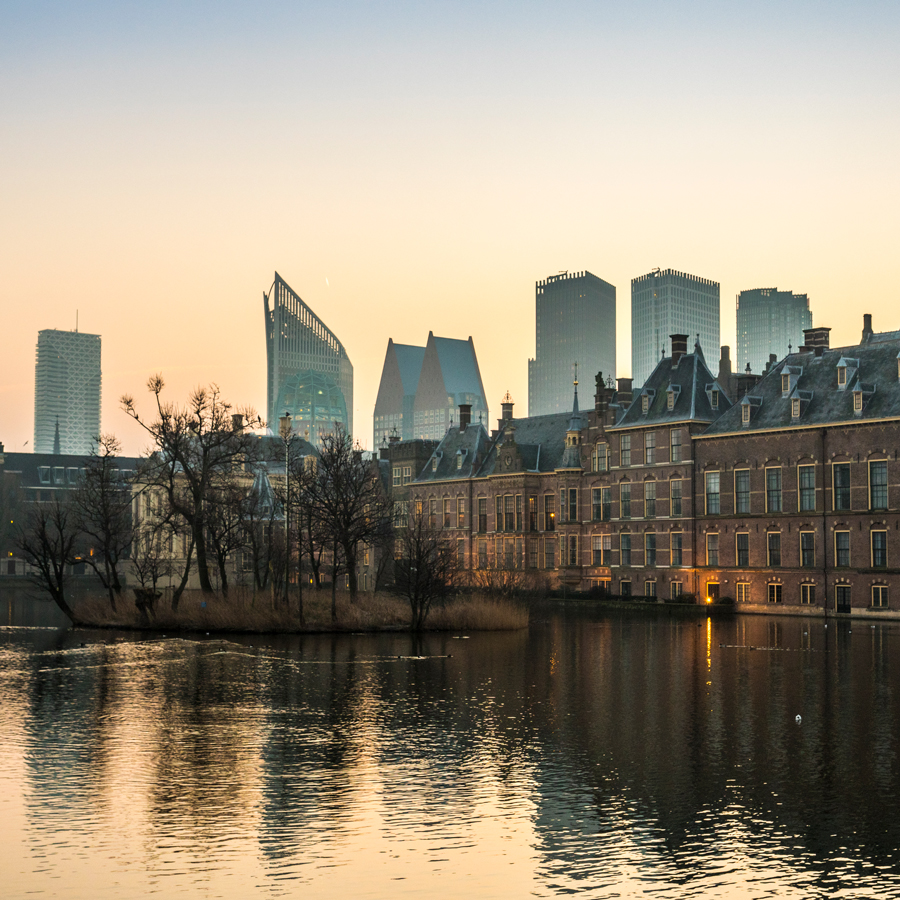 Het buitenhof in Den Haag met de vijver ervoor en hoogbouw op de achtergrond, warm licht