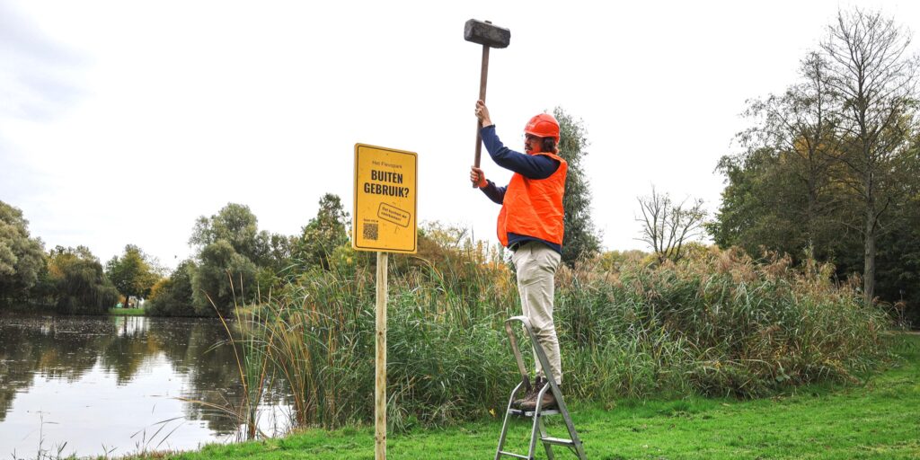Foto van iemand die Buiten Gebruik-bord bij zwemplas plaatst.