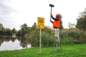 Foto van iemand die Buiten Gebruik-bord naast een zwemplas plaatst.