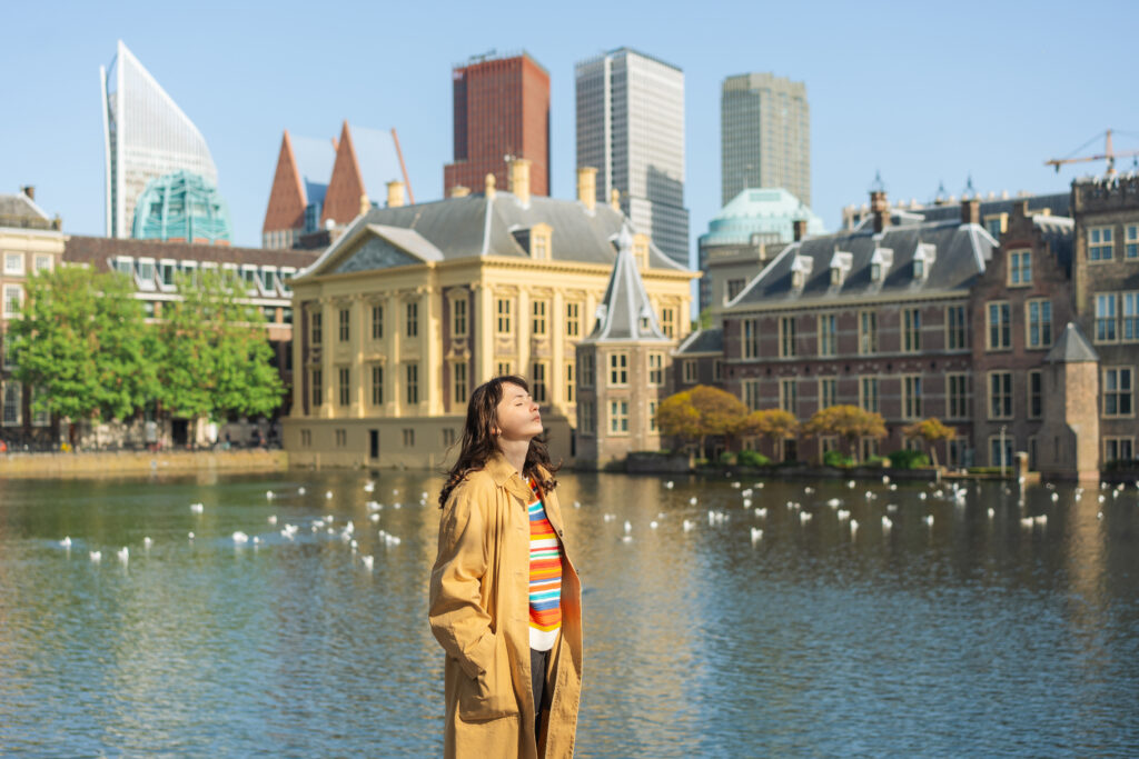Vrouw staat in Den Haag voor het torentje en hofvijfer en kijkt met haar gezicht de zin in.