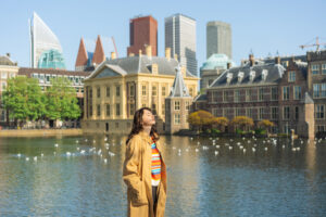 Vrouw staat in Den Haag voor het torentje en hofvijfer en kijkt met haar gezicht de zin in.