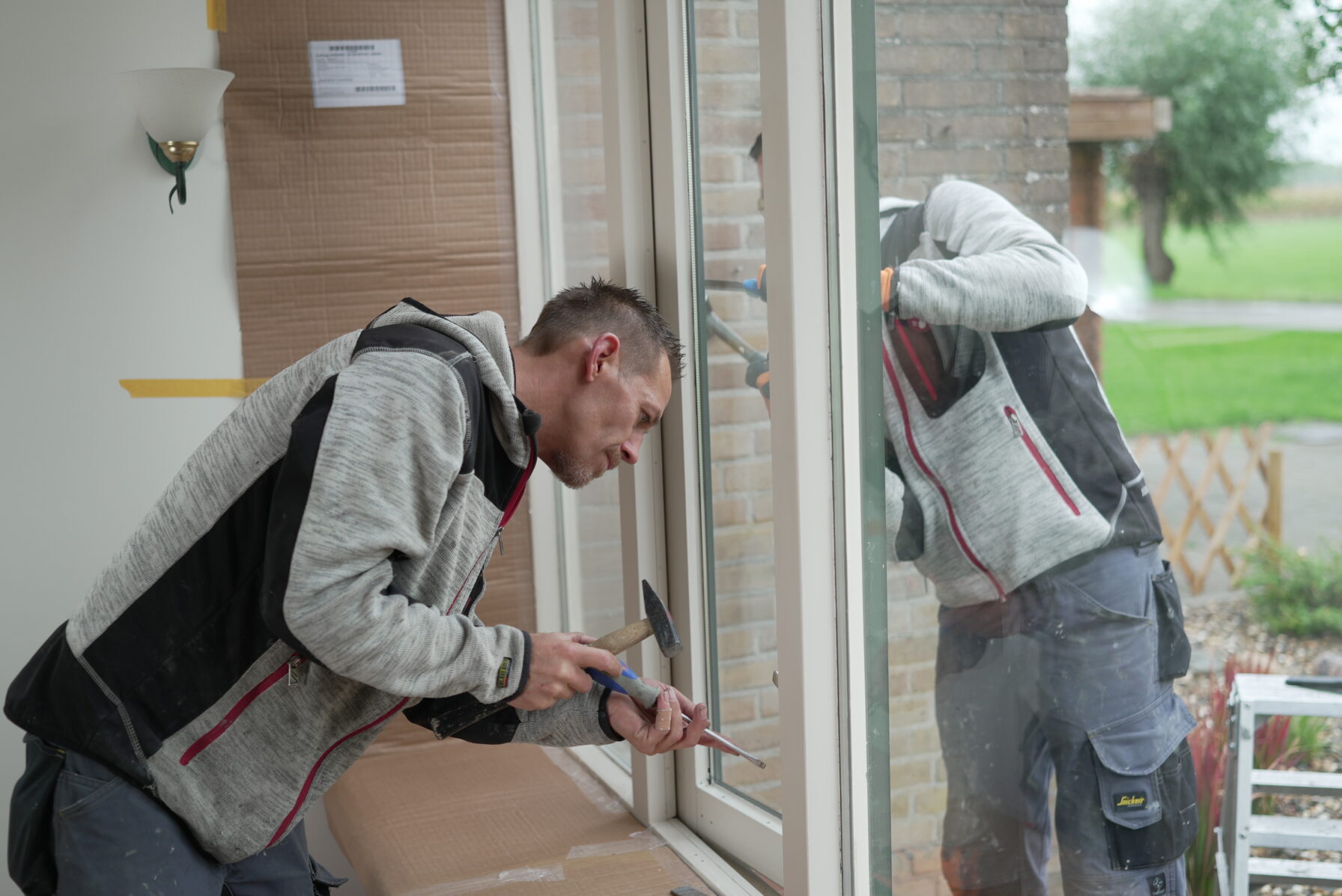 Twee mannen vervangen het glas in een kozijn