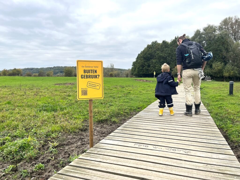 Foto van man met kind in natuurgebied, naast bord met 'Dit natuurgebied buiten gebruik? Dat moeten we voorkomen'