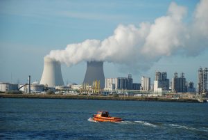 kerncentrale met rookwolken tegen de horizon met de zee ervoor