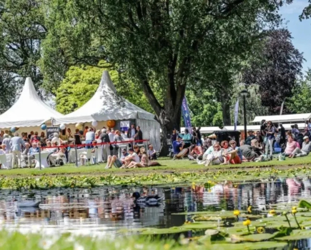 witte feesttenten in het park met allemaal mensen er om heen