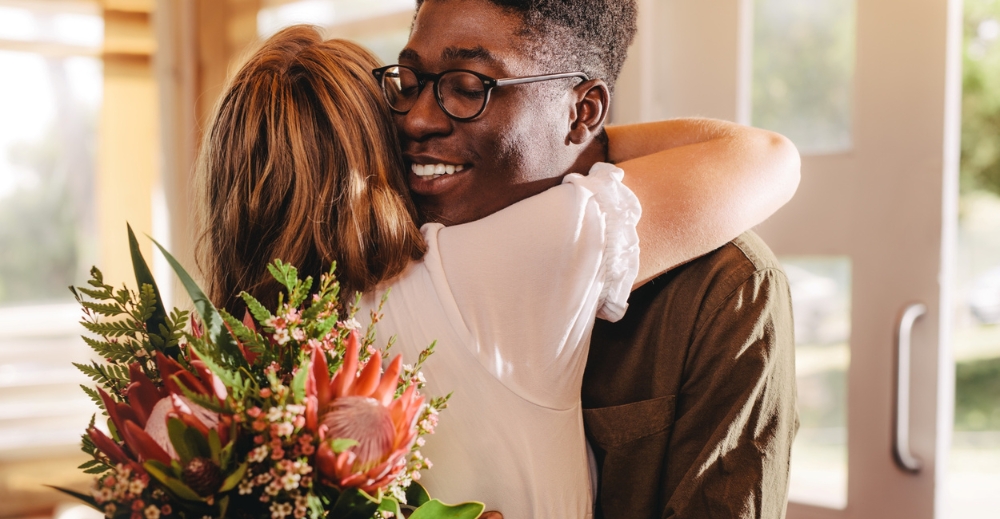 Man en vrouw in omhelzing met bloemen in de hand