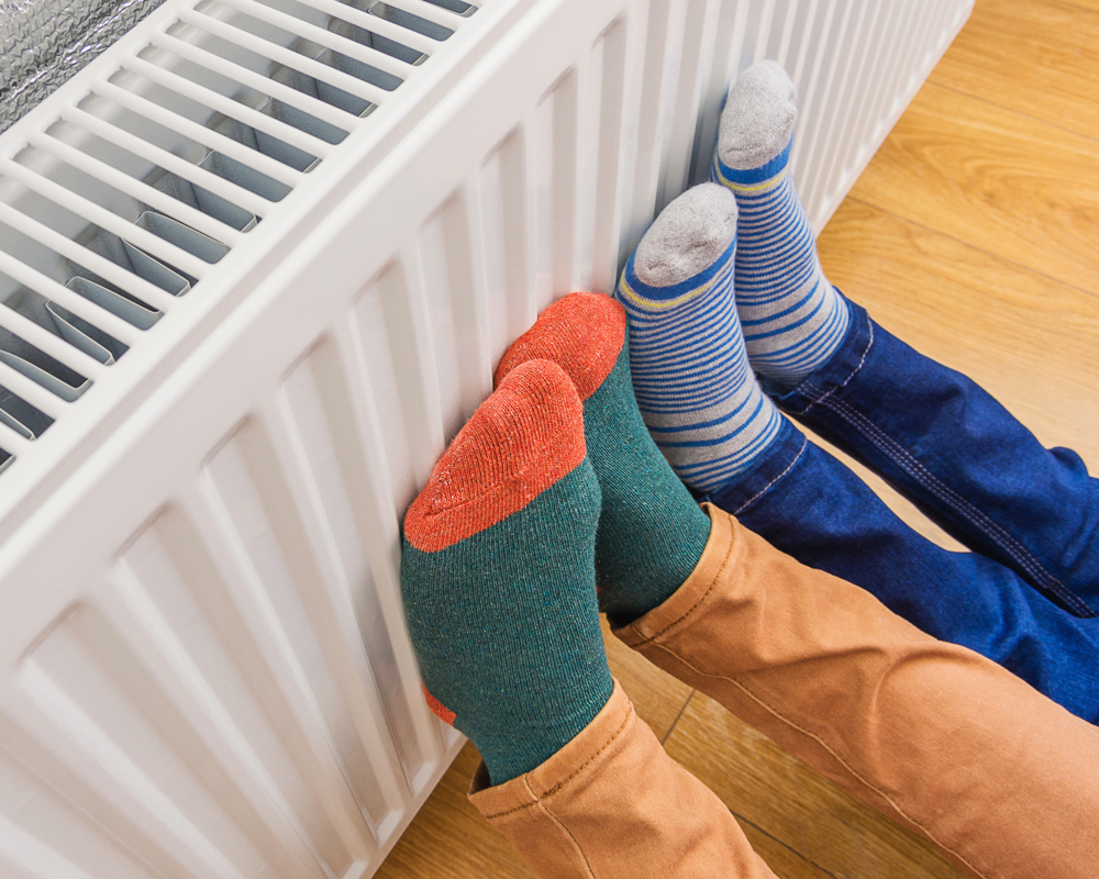 Twee paar voeten in kleurrijke sokken tegen een witte radiator