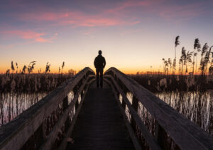 Man op brug met zonsondergang