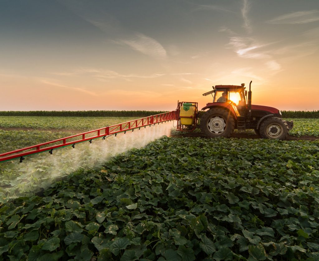 tractor sproeit bestrijdingsmiddelen op een akker met gewassen