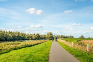 Twee mensen fietsen door groen Nederlands landschap