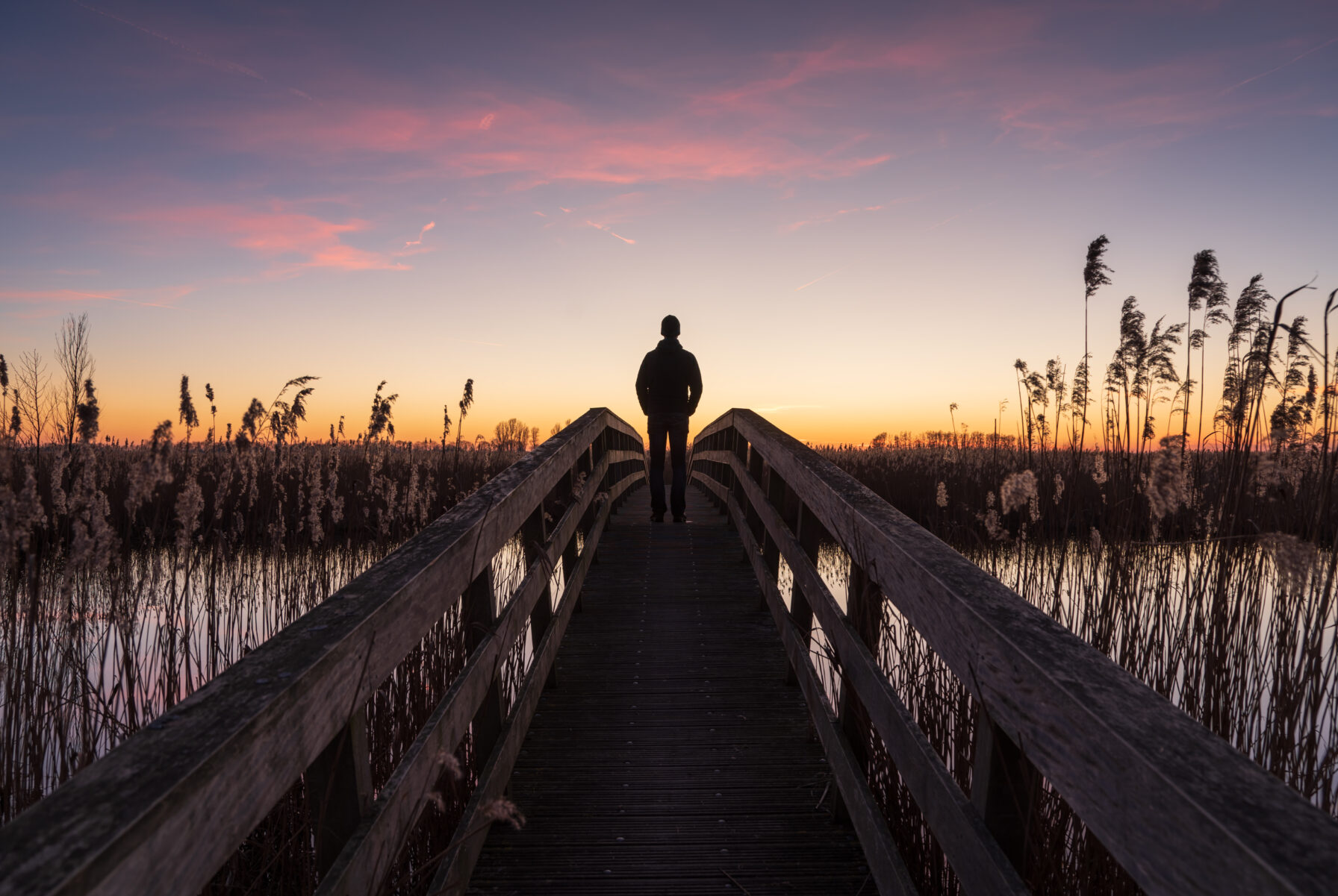 Man op brug kijkt naar zonsondergang