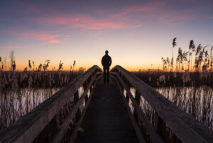 Man op brug kijkt naar zonsondergang