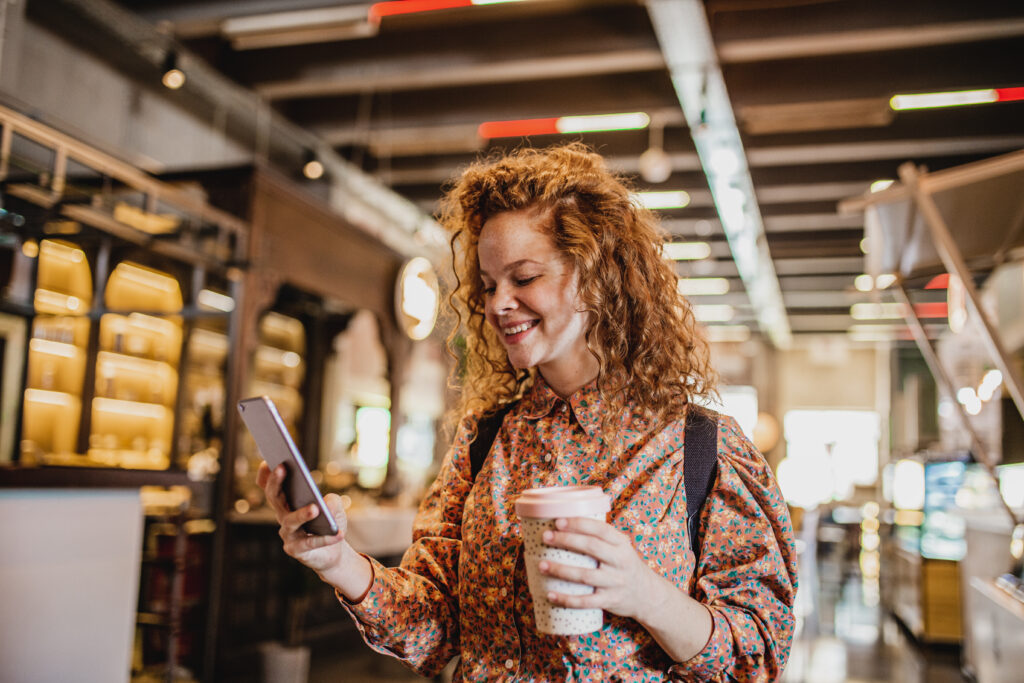 vrouw met mobiel en koffiebeker