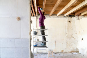 Vrouw is aan het klussen in huis en staat op een steiger
