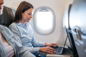 Vrouw werkt op laptop in vliegtuig
