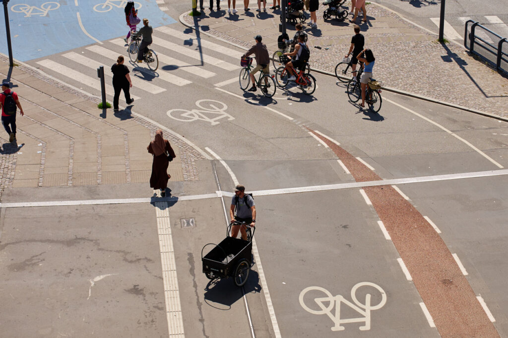 Luchtfoto van een druk stadskruispunt met fietsers, voetgangers en een bakfiets op goed aangelegde fiets- en looproutes