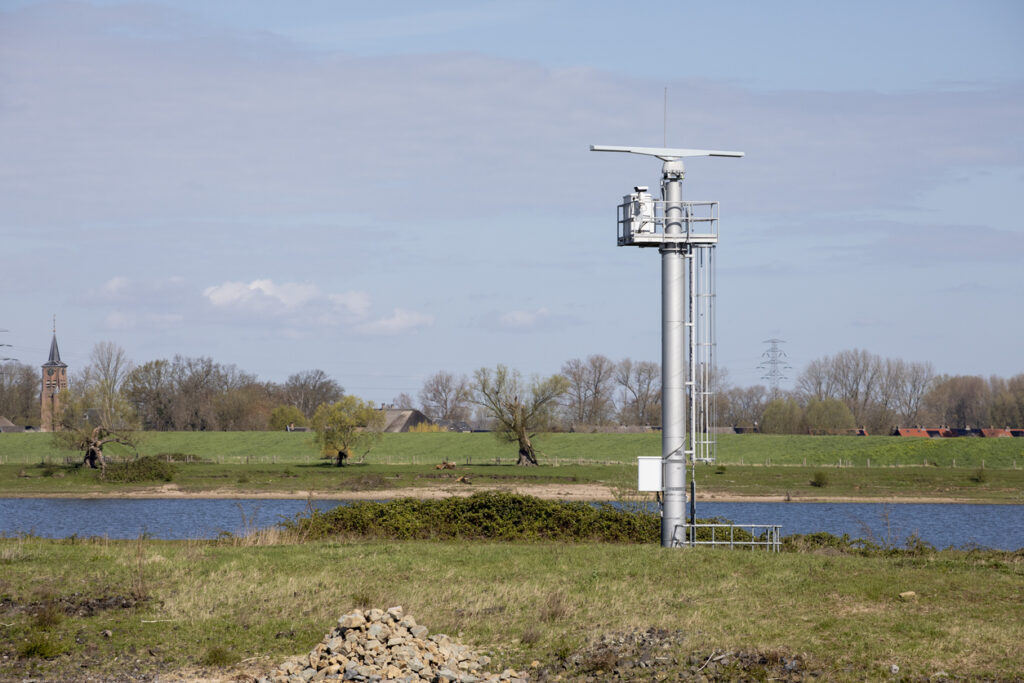 Een milieu meetstation met radartechnologie op een rivieroever in een natuurgebied
