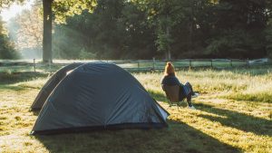vrouw zit voor de tent in een stoel