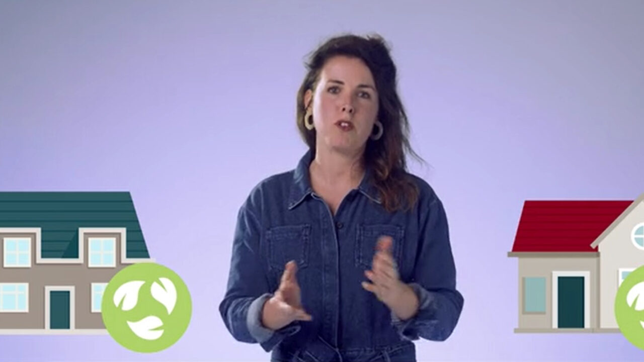 presentatrice staat voor een paars scherm met iconen van huizen