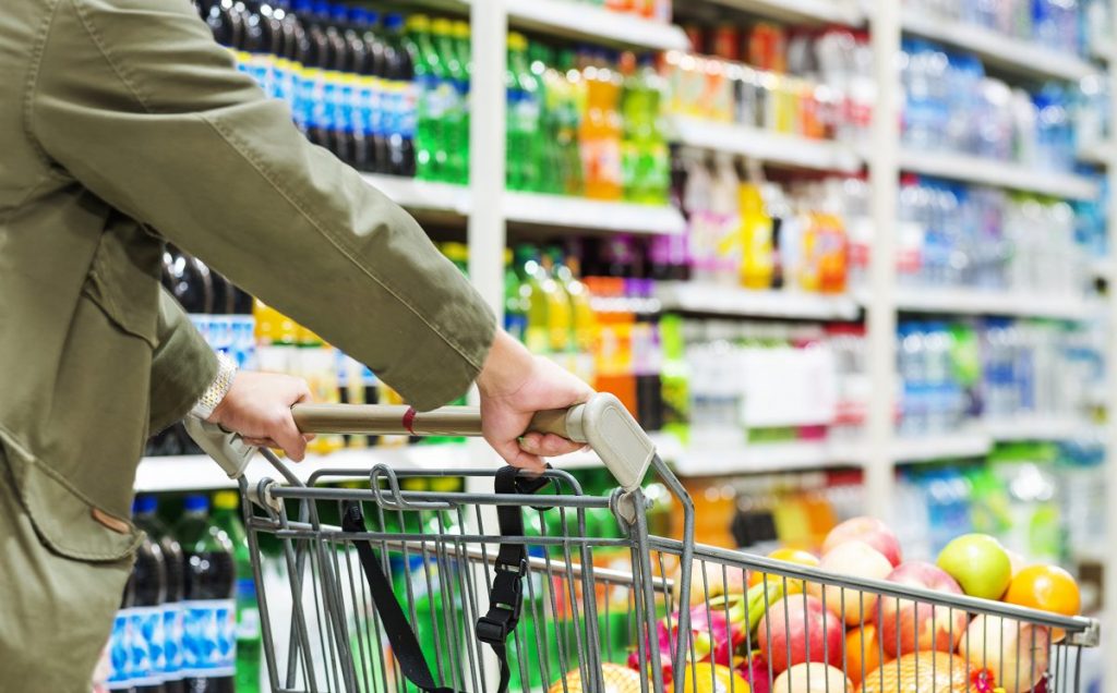 Winkelwagen in de supermarkt, geduwd door een persoon